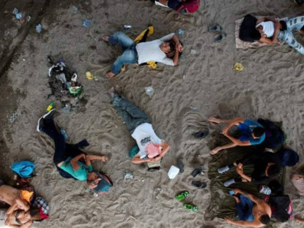 Migrantes hondureños de la Caravana Migrante descansan en la orilla del río Suchiate, frontera natural con Guatemala. (Photo by Carlos ALONZO / AFP)