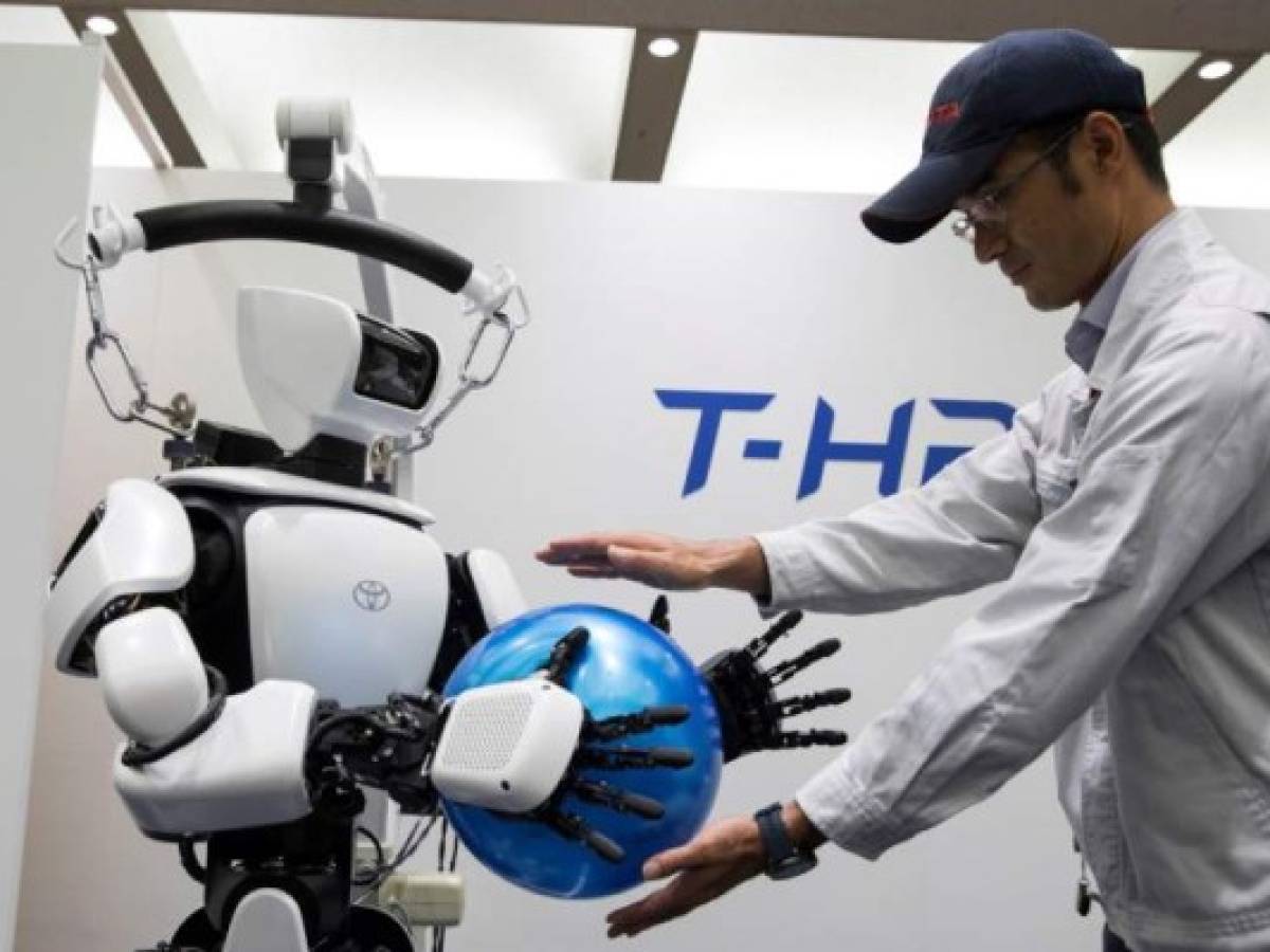 In this picture taken on July 18, 2019 an employee of Toyota Motor Corp. demonstrates the T-HR3 humanoid robot which will be used during the Tokyo 2020 Olympic and Paralympic Games, in Tokyo. - A roster of Olympic robots that will do everything from welcoming visitors to transporting javelins has been unveiled as Tokyo works to showcase Japanese technology at next year's Summer Games. (Photo by Behrouz MEHRI / AFP)