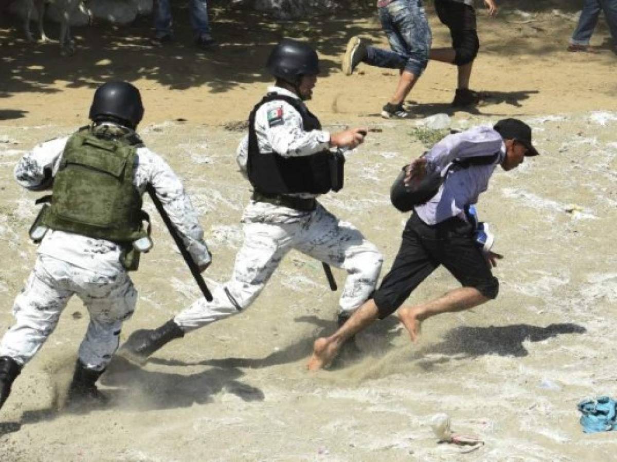 Cientos de migrantes centroamericanos, mayoritariamente hondureños, que quieren llegar a Estados Unidos comenzaron a cruzar este lunes a México desde Guatemala mientras eran contenidos a golpe de gases lacrimógenos por guardias nacionales mexicanos en el río Suchiate. Foto / AFP