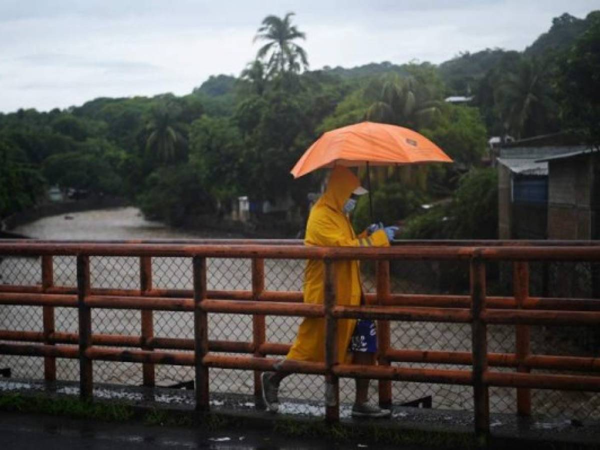 A man crosses a bridge over the Chilama River in La Libertad one of the areas hardest hit by Tropical Storm Amanda in El Salvador, on June 1, 2020. - Storm Amanda left a trail of destruction and death as it passed through northern Central America, where 18 people died and countless houses and roads were devastated by the cyclone, especially in El Salvador, the country worst beaten. (Photo by Marvin RECINOS / AFP)