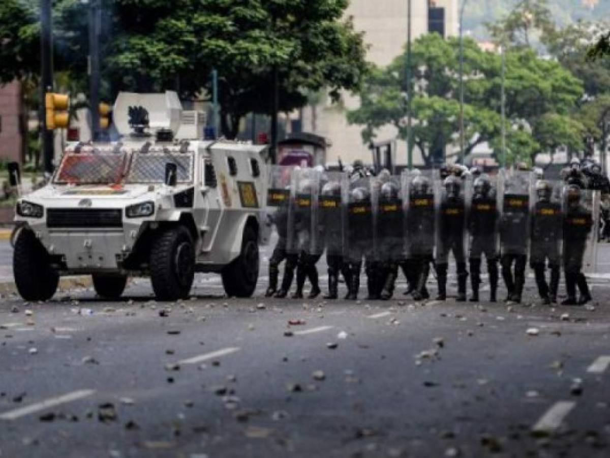 Members of the National Guard crack down on opposition demonstrators during a march against President Nicolas Maduro, in Caracas on April 26, 2017. Venezuelan riot police fired tear gas to stop anti-government protesters from marching on central Caracas, the latest clash in a wave of unrest that, up to now, has left 26 people dead. / AFP PHOTO / FEDERICO PARRA