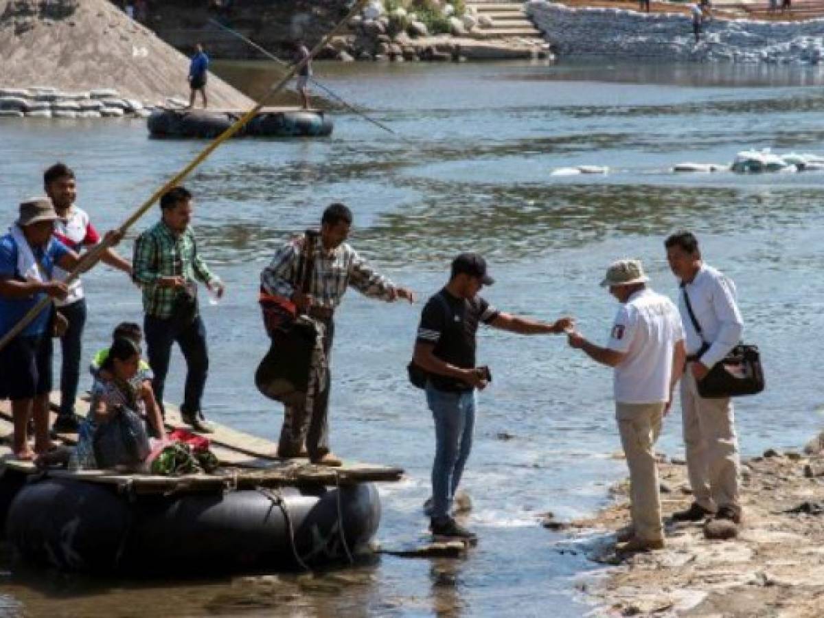 Un oficial de migración mexicana revisa documentos (Der.) en el río Suchiate, frontera natural con Tecún Umán, Guatemala. (Photo by ISAAC GUZMAN / AFP)