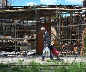 Un hombre pasa frente a una tienda destruida en las afueras del norte de Kharkiv el 7 de junio de 2022, en medio de la invasión rusa de Ucrania