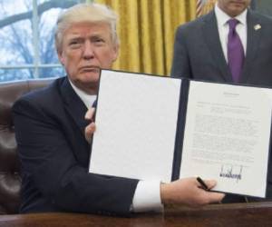 US President Donald Trump holds up an executive order withdrawing the US from the Trans-Pacific Partnership after signing it in the Oval Office of the White House in Washington, DC, January 23, 2017.Trump the decree Monday that effectively ends US participation in a sweeping trans-Pacific free trade agreement negotiated under former president Barack Obama. / AFP PHOTO / SAUL LOEB