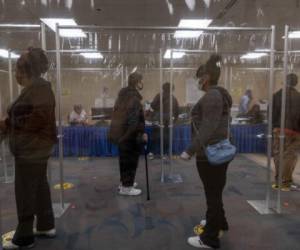 Residents of Lucas County, Ohio wait in line behind plastic barriers and stand six feet apart to help protect people from Coronavirus (Covid-19) during early voting in the US state of Ohio on October 6,2020 in Toledo, Ohio. (Photo by SETH HERALD / AFP)