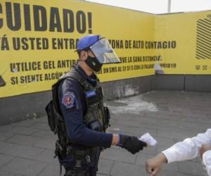A policeman checks the temperature of a visitor at the 'Central de Abasto' wholesale market in Mexico City on October 27, 2020, amid the new coronavirus pandemic. (Photo by ALFREDO ESTRELLA / AFP)