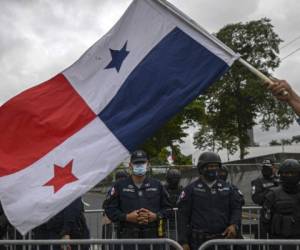 A University student flutters a Panamanian flag in front of a line of police during a march to protest alleged corruption and hunger amid the new coronavirus pandemic outside the National Assembly in Panama City, on July 1, 2020. - Panama's President Laurentino Cortizo warned Wednesday that his country faced a worsening health crisis in the coming weeks due to the coronavirus pandemic. In an Instagram message marking his first year in office, Cortizo said the virus was subjecting his country to 'unprecedented and demanding tests.' Panama is the Central American country worst hit from the pandemic, with more than 33,500 infections and 631 deaths, according to official figures. (Photo by Luis ACOSTA / AFP)