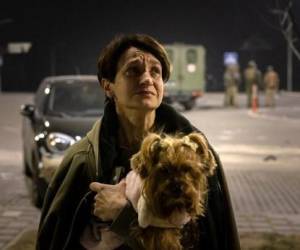Una mujer carga a su perro tras dejar su apartamento después de un ataque en Kiev el 20 de marzo de 2022. (Photo by FADEL SENNA / AFP)