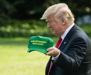 US President Donald Trump displays caps reading 'Make our Farmers Great Again' while walking to board Marine One as he departs the White House in Washington, DC, on August 30, 2018 for Indiana. / AFP PHOTO / NICHOLAS KAMM