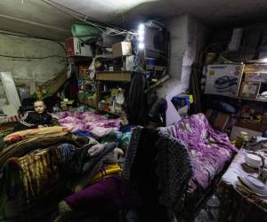 Hleb Petrova, de 14 años, se sienta en su cama para dormir en un sótano donde se refugia y vive con su familia, parientes y vecinos que buscan más protección debido al intenso bombardeo de las fuerzas rusas en la ciudad de Bakhmut, en el este de Ucrania, el 21 de diciembre de 2022. (Foto de Sameer Al-DOUMY / AFP)
