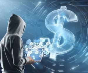 cyber attack concept with hacker in grey hoody with laptop and multimedia icons on screen. digital dollar sign background.