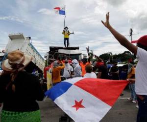 A man flutters a Panamanian flag on top of a truck as the Pan-American highway remains blocked in Chame, Panama, on July 14, 2022. - Panama's government is facing continuous protests against rising inflation and corruption. Demonstrations called by the Central American country's numerous unions have been taking place for the last two weeks, during which some main highways were blocked. (Photo by ROGELIO FIGUEROA / AFP)