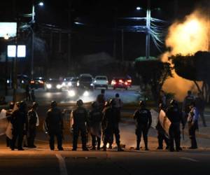 Members of the militar police release tear gas to the protestants in Tegucigalpa on June 19, 2019, during a day of protests against government reforms. - Thounsands of teachers, doctors and students have been staging protest against the government of Honduran President Juan Orlando Hernandez for measures they say will privatize health and education services. (Photo by ORLANDO SIERRA / AFP)