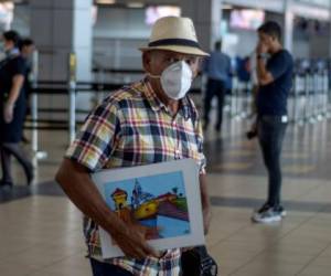 A vendor of paintings wears a face mask as a preventive measure against the spread of the new coronavirus, COVID-19, at Tocumen International Airport in Panama City on March 16, 2020. - The Panamanian government has now added a ban to flights from Asia, after the suspension of flights from Europe on Friday, as part of the measures to counter the novel coronavirus. (Photo by Luis ACOSTA / AFP)