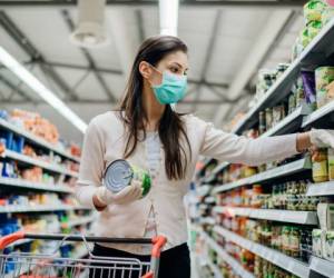 Woman preparing for pathogen virus pandemic spread quarantine.Choosing nonperishable food essentials.Budget buying at a supply store.Pandemic quarantine preparation.Emergency to buy list