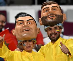 <i>Los aficionados al fútbol con máscaras del delantero portugués Cristiano Ronaldo y el delantero argentino Lionel Messi posan antes del partido de fútbol de la eliminatoria por el tercer puesto de la Copa Mundial de Qatar 2022 entre Croacia y Marruecos en el Estadio Internacional Khalifa en Doha el 17 de diciembre de 2022. (Foto de Paul ELLIS / AFP)</i>