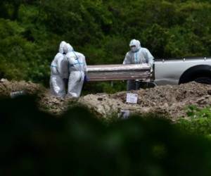Agents of the Police Investigations Direction (DPI), wearing protective suits, bury an alleged victim of COVID-19 in an an annex of the Parque Memorial Jardin de los Angeles cemetery, 14 km north of Tegucigalpa, on July 4, 2020. (Photo by ORLANDO SIERRA / AFP)