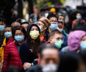 People wearing facemasks as a preventative measure following a coronavirus outbreak which began in the Chinese city of Wuhan, line up to purchase face masks from a makeshift stall after queueing for hours following a registration process during which they were given a pre-sales ticket, in Hong Kong on February 5, 2020. - The new coronavirus which appeared late December has claimed nearly 500 lives, infected more than 24,000 people in mainland China and spread to more than 20 countries. (Photo by Anthony WALLACE / AFP)