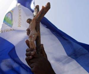 A person holds a cross as during the arrival of the students of the National Autonomous University of Nicaragua (UNAN), who hid overnight in a church during an attack of government forces, at the Cathedral in Managua, on July 14, 2018.Government forces in Nicaragua on Saturday shot dead two young men at a protest site in a church, the clergy said, on the third day of nationwide demonstrations against President Daniel Ortega, a former revolutionary hero now accused of authoritarianism. / AFP PHOTO / MARVIN RECINOS