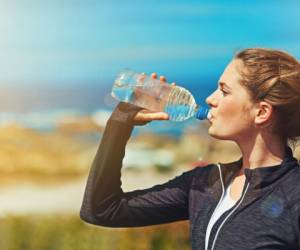 Shot of a sporty young woman drinking water outdoors