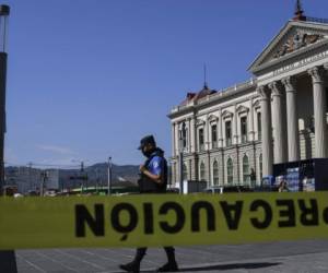 A municipal police officer is seen behind a yellow tape preventing pedestrian to access the Gerardo Barrios square in front of the National Palace in San Salvador on March 17, 2020 to avoid the concentration of people as a precautionary measure against the spread of the new coronavirus, COVID-19. - The Salvadoran government increased prevention measures against COVID-19. (Photo by Yuri CORTEZ / AFP)