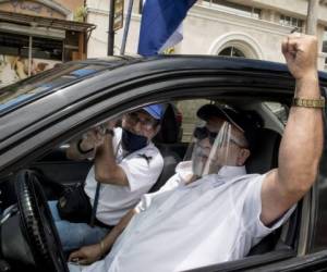 Dos hombres forman parte de una protesta donde piden flexibilidad de medidas en Costa Rica. Foto Ezequiel BECERRA / AFP)