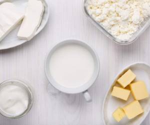 Different type of dairy products on white wooden background. Milk, cottage cheese, soft cheese, yogurt, butter. Top view.