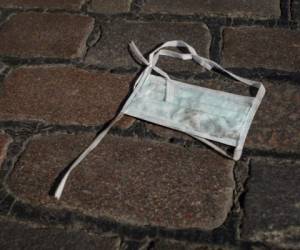 A thrown-away surgical mask, worn by many people during the new coronavirus COVID-19 pandemic, lays on the ground in Berlin's Kreuzberg district on March 26 2020. (Photo by David GANNON / AFP)
