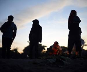 Central American migrants -heading in a caravan for the US- wake up on the bank of the Suchiate River, where they spent the night, in Ciudad Hidalgo, Mexico, after crossing from Tecun Uman, Guatemala, on January 21, 2020. - Some 500 Central Americans, from the so-called '2020 Caravan', crossed Monday from Guatemala to Mexico, but over 400 were intercepted when National Guardsmen fired tear gas at them. (Photo by ALFREDO ESTRELLA / AFP)