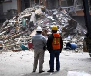 Technicians watch as a building seriously damaged by the September 19 earthquake is demolished in Mexico City on October 17, 2017. An estimated 1,800 buildings in Mexico City suffered serious damage during the 7.1-magnitude quake that hit the country last month, and will have to be repaired or demolished. / AFP PHOTO / PEDRO PARDO