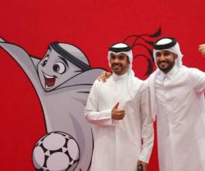 Los qataríes posan junto a una ilustración de la mascota de la Copa Mundial de la FIFA Qatar 2022 “La’eeb” en el centro de servicio Hayya en la capital Doha el 16 de octubre de 2022. - Qatar dijo que más de 1,5 millones de personas han solicitado el pase obligatorio para la Copa del Mundo de fútbol, que comienza el 20 de noviembre. (Foto de KARIM JAAFAR / AFP)