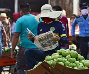 A man wears a face mask against the spread of the new coronavirus as he reads a newspaper at a market in Tegucigalpa on April 8, 2020. - 312 cases of COVID-19 were reported in Honduras, with 22 deaths. (Photo by ORLANDO SIERRA / AFP)