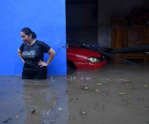 Una mujer observa cómo sube el agua afuera de su casa en la colonia Santa Lucía, Ilopango, en El Salvador. Foto AFP