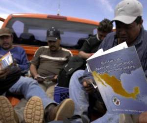 Migrants seeking to cross the US-Mexico border read the 'Cartilla de derechos humanos para los migrantes', a booklet distributed by Grupo Beta -a Mexican unit that protects and assists migrants-, as they sit in a pickup truck about 200 meters from the US-Mexican border west of Agua Prieta, Sonora, Mexico, 06 April 2005. The group of 18 migrants, 15 from the Mexican state of Puebla, were picked up by Grupo Beta and warned not to cross the border near territory watched by the Minuteman Project, a volunteer group in the US watching the southeastern Arizona border to deter illegal immigration. The migrants were then taken to Agua Prieta and dropped off near a hotel where they would stay for the night. The group said they intended to cross the border elsewhere. . AFP PHOTO/NICHOLAS ROBERTS / AFP PHOTO / NICHOLAS ROBERTS