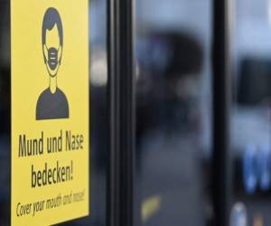 A sign informing commuters to cover mouth and nose with a mask is seen on a bus in the city of Munich, southern Germany, on November 11, 2021, amid a surge of infections during the ongoing coronavirus (Covid-19) pandemic. - Germany needs further coronavirus restrictions to combat a record surge in infections and 'get through this winter', German would-be chancellor Scholz said on November 11, calling a meeting with state premiers to decide new curbs. The country recorded 50,196 new cases in the past 24 hours on November 11, according to the Robert Koch Institute (RKI) health agency -- the first time the figure has exceeded 50,000. (Photo by Christof STACHE / AFP)