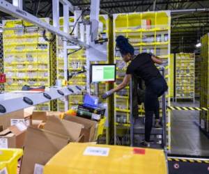 A woman works at a distrubiton station at the 855,000-square-foot Amazon fulfillment center in Staten Island, one of the five boroughs of New York City, on February 5, 2019. - Inside a huge warehouse on Staten Island thousands of robots are busy distributing thousands of items sold by the giant of online sales, Amazon. (Photo by Johannes EISELE / AFP)