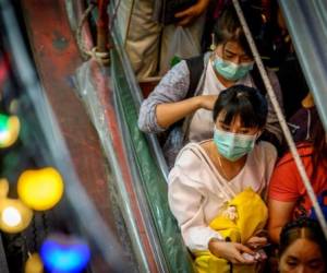 Commuters with protective facemasks sit in a canal boat at Pratunam Pier in Bangkok on January 30, 2020. - A Thai surgical mask factory, producing 10 million masks a month, increased working hours to cope with the rising demand following an outbreak of SARS-like virus in China, with their product exported mostly to US and Europe the rest sold on the domestic market. (Photo by Mladen ANTONOV / AFP)