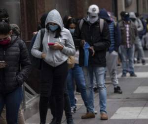 (FILES) In this file photo taken on May 28, 2020, people wear face masks as they queue to get an unemployment insurance outside the Chilean Unemployment Funds Administration headquarters in Santiago. - The coronavirus pandemic has left a trail of death around the world and has hit Latin America in particular, the new epicentre of a crisis that is shattering an already precarious labour market. (Photo by Martin BERNETTI / AFP)
