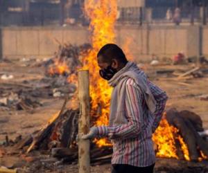 A man walks past burning funeral pyres of people, who died due to the coronavirus disease (COVID-19), at a crematorium ground in New Delhi, India, April 22, 2021. REUTERS/Danish Siddiqui