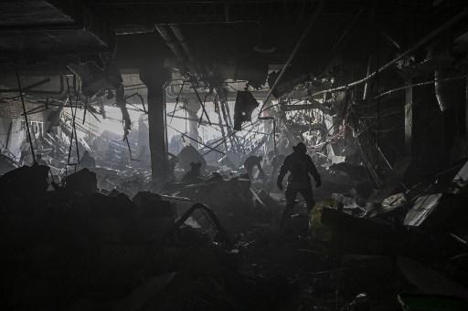 Un ucraniano camina tras los restos dentro de Retroville, tras un ataque ruso en el noroeste de Kiev el 21 de marzo de 2022. - Murieron al menos seis personas tras bombardeos en la noche. (Photo by ARIS MESSINIS / AFP)