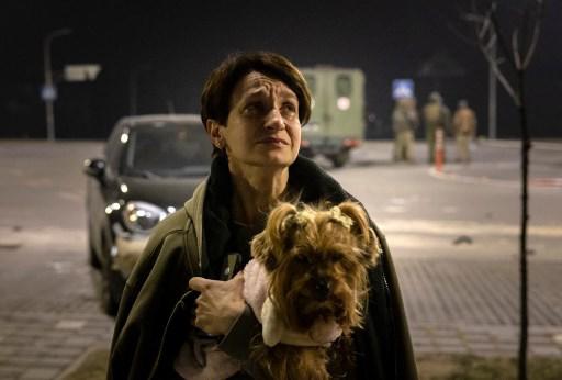 Una mujer carga a su perro tras dejar su apartamento después de un ataque en Kiev el 20 de marzo de 2022. (Photo by FADEL SENNA / AFP)