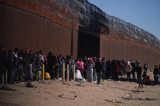 Hundreds of migrants line up to be processed by US Border Patrol under the Stanton Street Bridge after illegally entering the US, in El Paso, Texas, on December 22, 2022. (Photo by Allison Dinner / AFP)