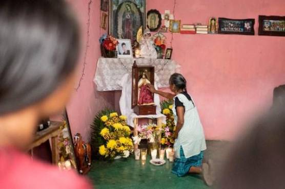 Un familiar de Misael Olivares, de 16 años, reportado como uno de los 53 migrantes que murieron dentro de un tráiler en San Antonio, Texas, reza ante un altar en su casa en San Marcos Atexquilapan, estado de Veracruz, México, 1 de julio de 2022. (Foto por Héctor QUINTANAR / AFP)