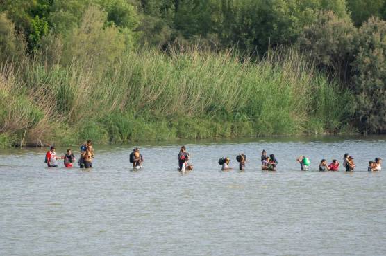 <i>Los migrantes cruzan el Río Grande desde el lado mexicano de la frontera hacia los EE. UU. el 16 de julio de 2023 vistos desde Eagle Pass, Texas. (Photo by SUZANNE CORDEIRO / AFP)</i>