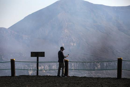 Un turista toma fotografías del cráter del volcán Santiago en el Parque Nacional Masaya en Masaya, Nicaragua, el 20 de abril de 2021, en la víspera del Día de la Tierra. FOTO OSWALDO RIVAS / AFP