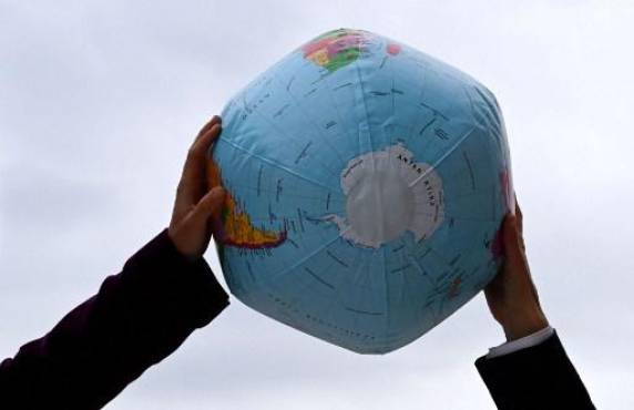 Un activista ambiental sostiene un globo inflable, que muestra el Polo Sur y la Antártida, durante una manifestación frente a la sede de las conversaciones exploratorias entre los principales miembros del partido socialdemócrata SPD, los Verdes y el partido democrático libre FDP el 15 de octubre de 2021, en Berlín. FOTO CHRISTOF STACHE / AFP