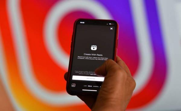 This illustration picture shows Instagram's new video feature 'Reels' on a smartphone in front of a screen showing an Instagram logo, on August 6, 2020 in Los Angeles. - Instagram on August 5 added a new short-form video feature to the image-focused platform in a direct challenge to TikTok. 'Reels' lets users record videos of up to 15 seconds and provides tools for editing, audio and effects, according to the Facebook-owned company. (Photo by Chris DELMAS / AFP)