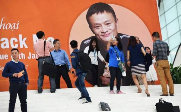 Estudiantes se fotografían frente a un afiche de Jack Ma, el hombre más rico de China, el cofundador de Alibaba Group en el Centro de Convenciones de Hanoi, Vietna, el 6 de noviembre de 2017. / AFP PHOTO / HOANG DINH NAM