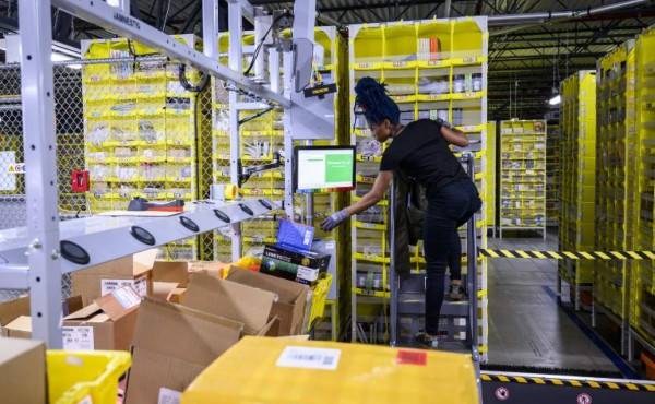 A woman works at a distrubiton station at the 855,000-square-foot Amazon fulfillment center in Staten Island, one of the five boroughs of New York City, on February 5, 2019. - Inside a huge warehouse on Staten Island thousands of robots are busy distributing thousands of items sold by the giant of online sales, Amazon. (Photo by Johannes EISELE / AFP)