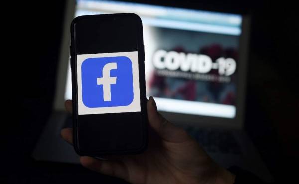 (FILES) In this file photo the Facebook logo is displayed on a mobile phone screen photographed on coronavirus COVID-19 illustration graphic background on March 25, 2020 in Arlington, Virginia. - Facebook said March 30, 2020 it was donating $100 million to support news organizations globally hurting from the coronavirus pandemic, citing the need for reliable information about the crisis.'The news industry is working under extraordinary conditions to keep people informed during the COVID-19 pandemic,' said Facebook's news partnerships director, Campbell Brown. (Photo by Olivier DOULIERY / AFP)
